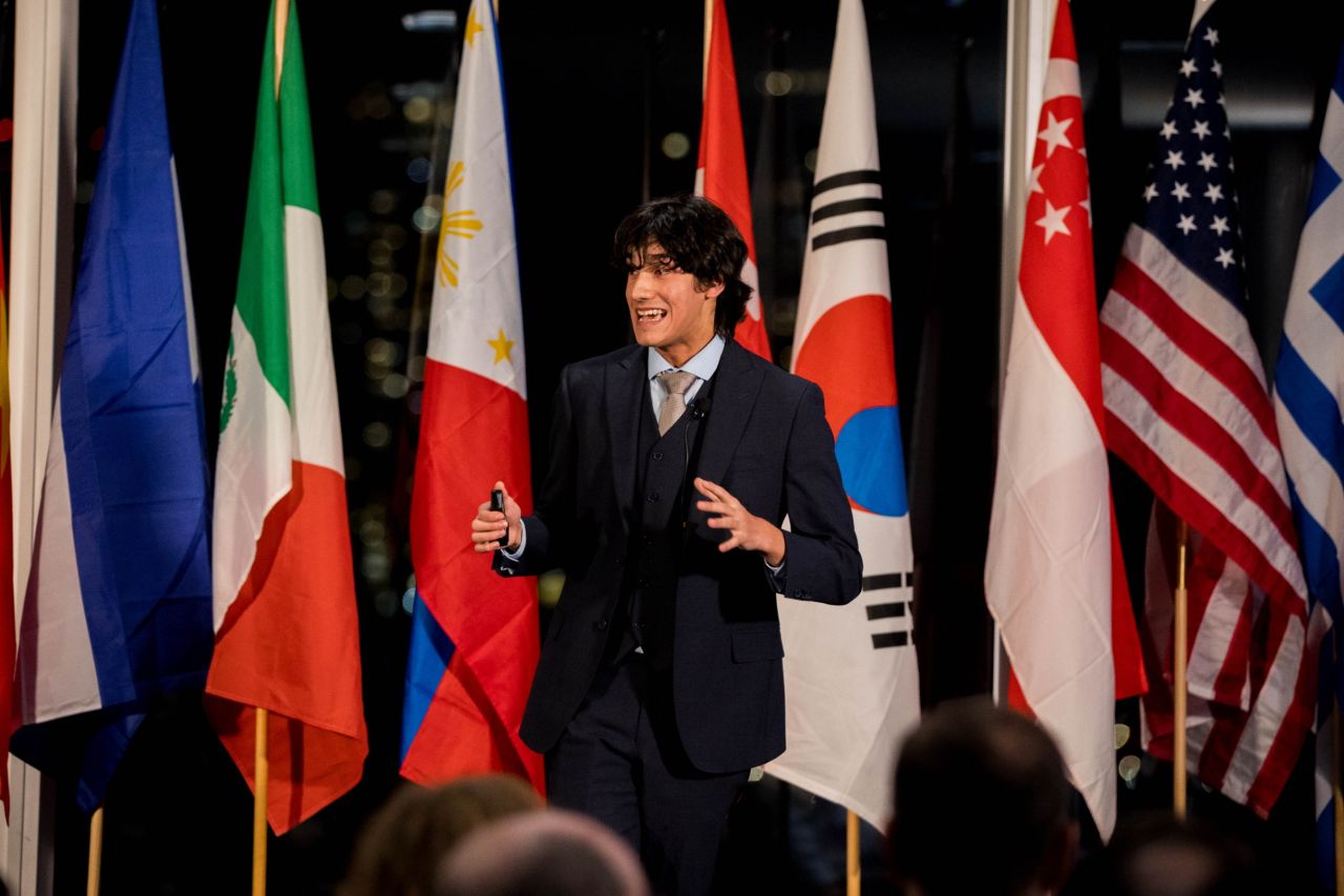 Carlos Morett presenting at an international stage with national flags behind him